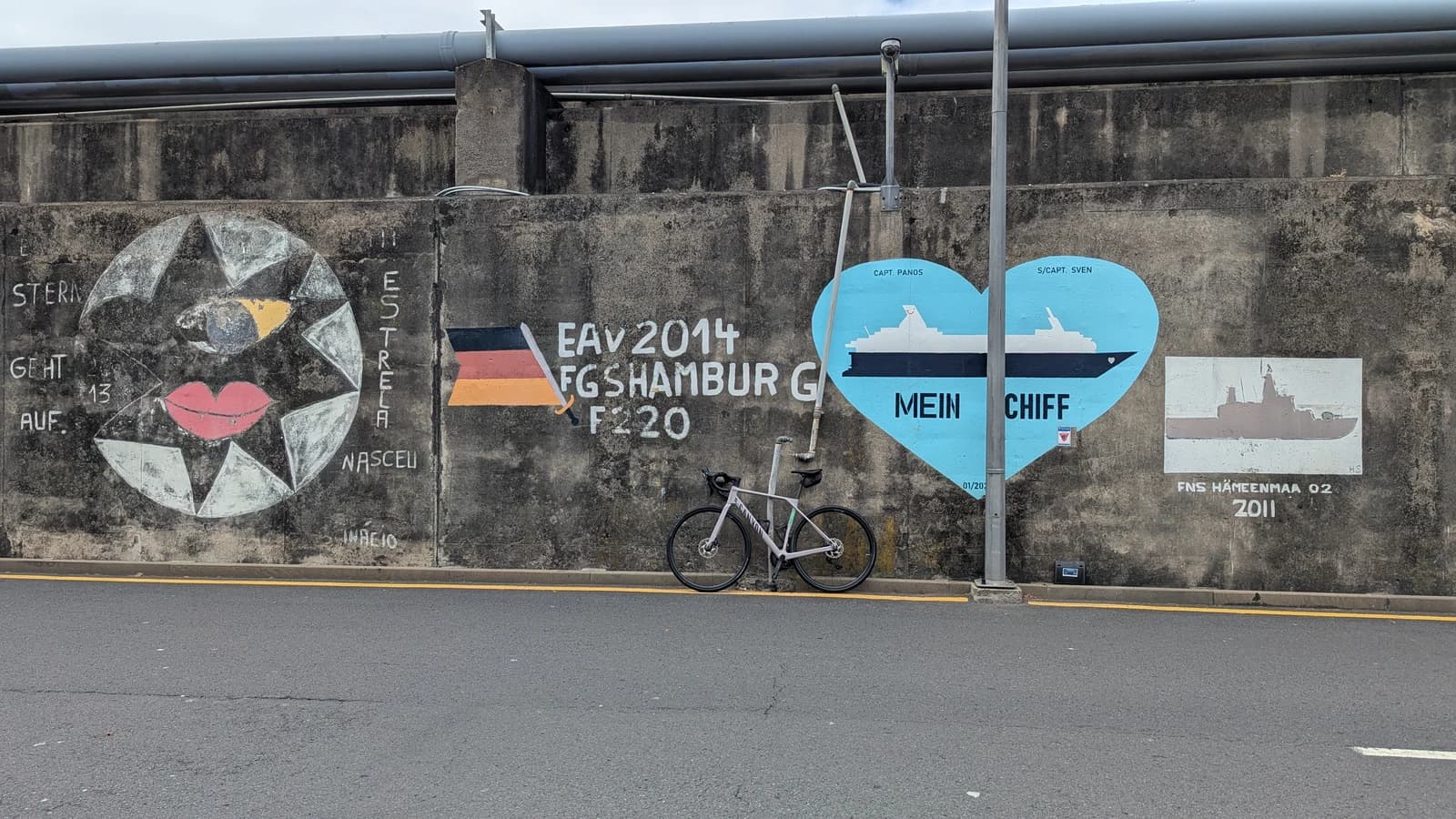 Велосипед в порту Мадейры у стены с надписью Hamburg