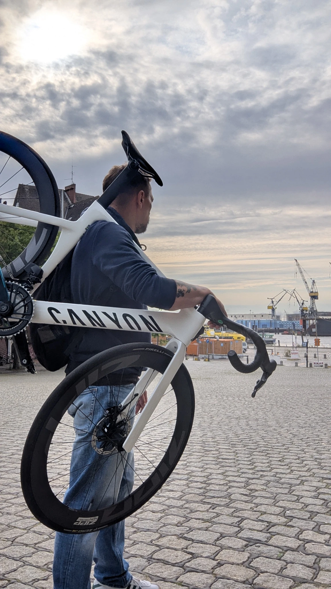 Александр несёт белый Canyon Aeroad CF SLX 8 AXS на плече у RAD RACE на Фишмаркте в Гамбурге